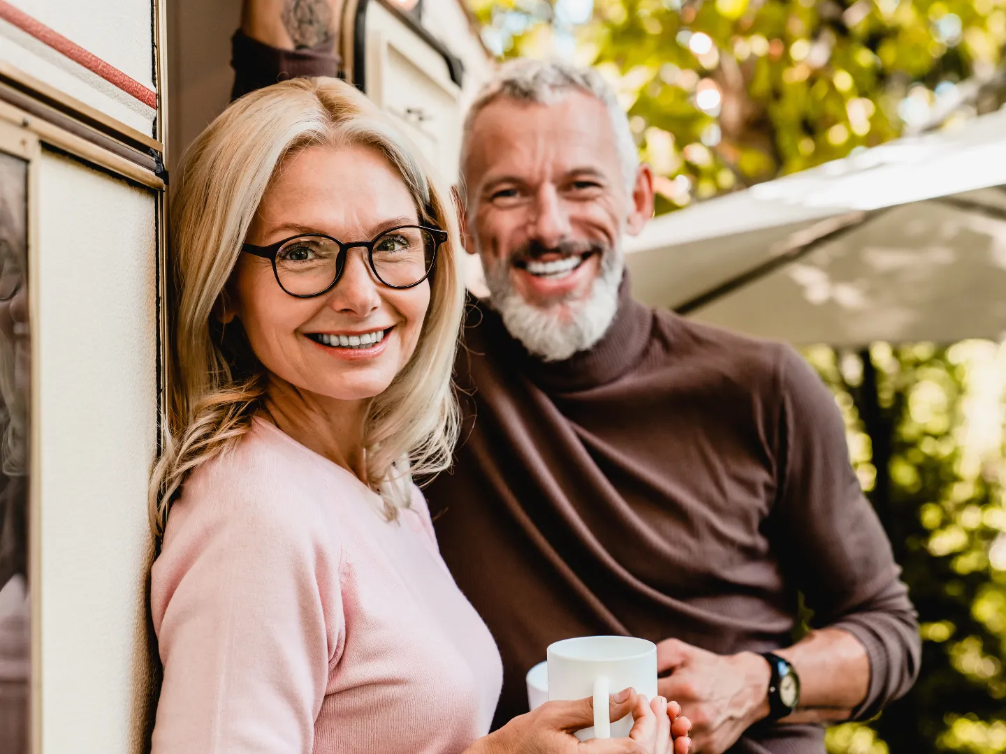 Couple smiling outdoors in the sun.