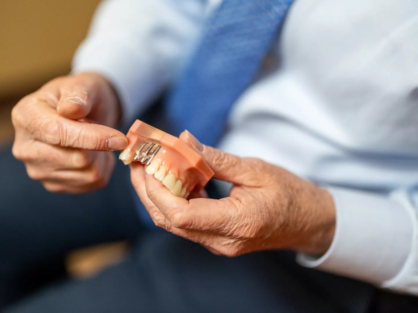 Close up of a dental implant model in the hands of a doctor as he shows a patient.