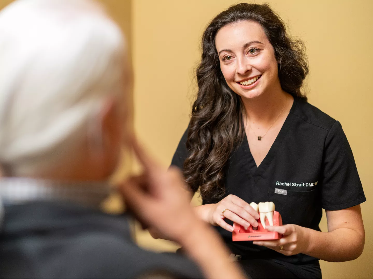 Dr. Strait warmly smiles during a consult while holding a dental model.