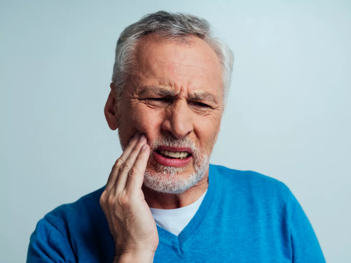 A man holds his mouth in pain.