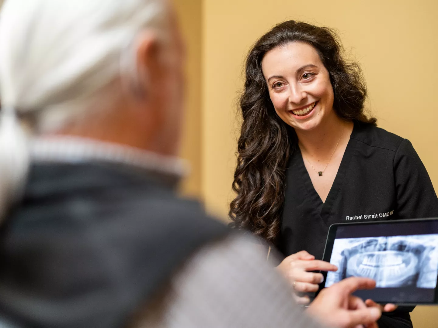 Dr. Strait smiles as she shows scans on a tablet to a patient.
