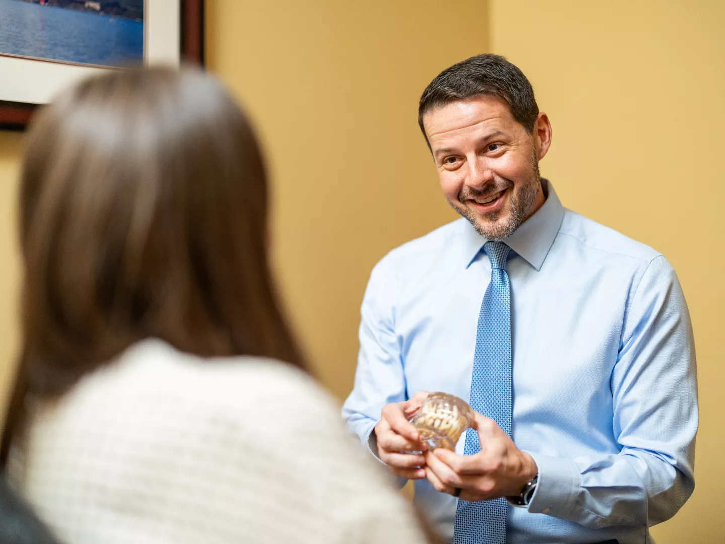 Dr. Brad Lewallen holds a dental model and consults with a patient.