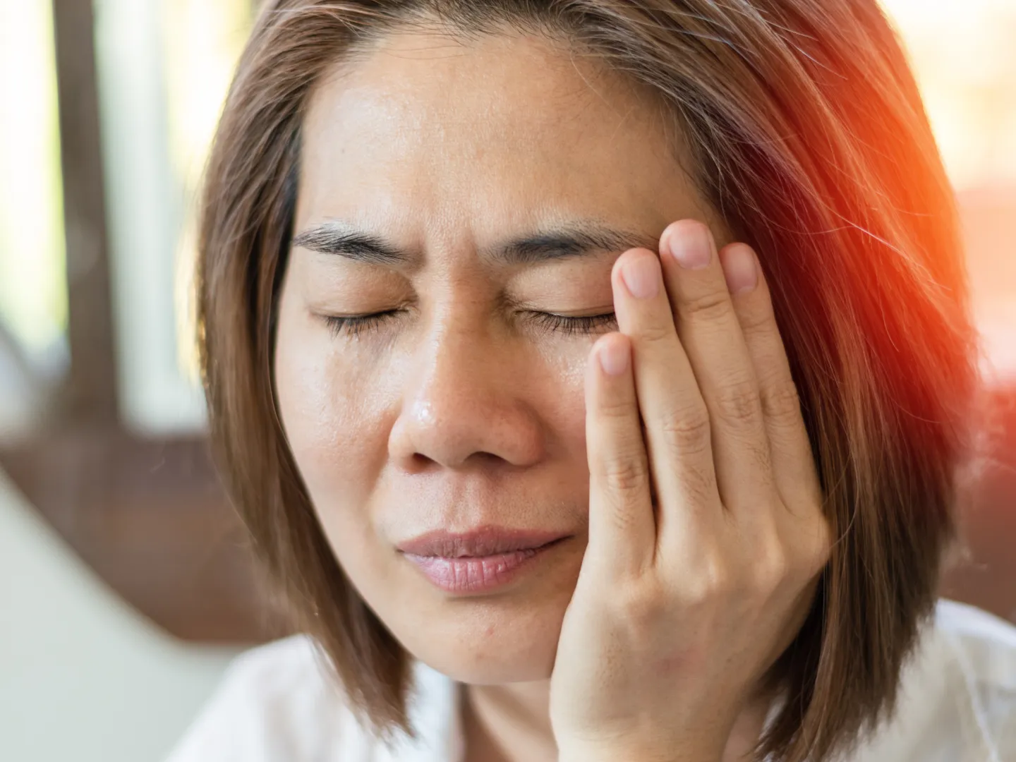 A woman holding her mouth in pain.